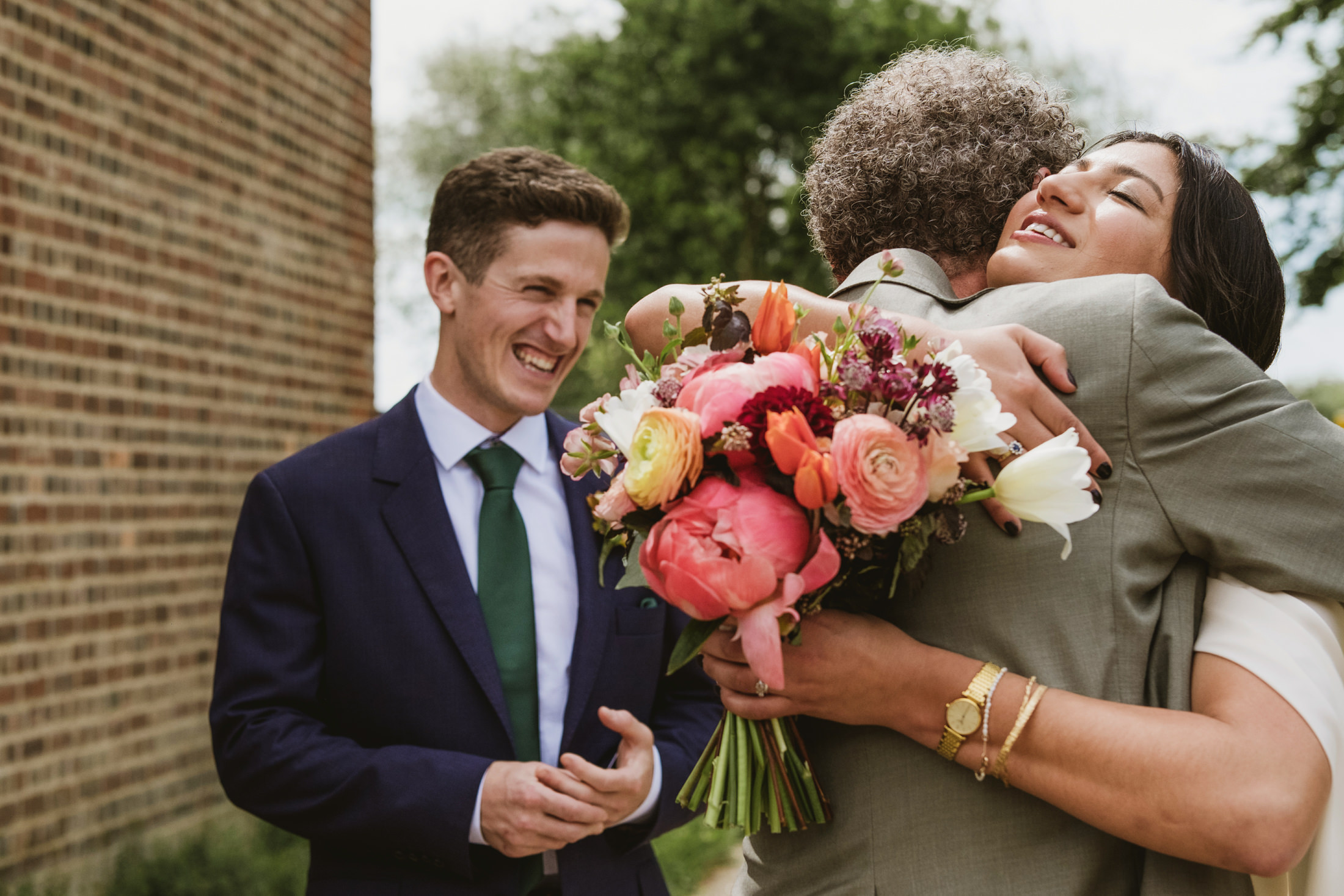 Smiling people hugging, holding colourful bouquet.