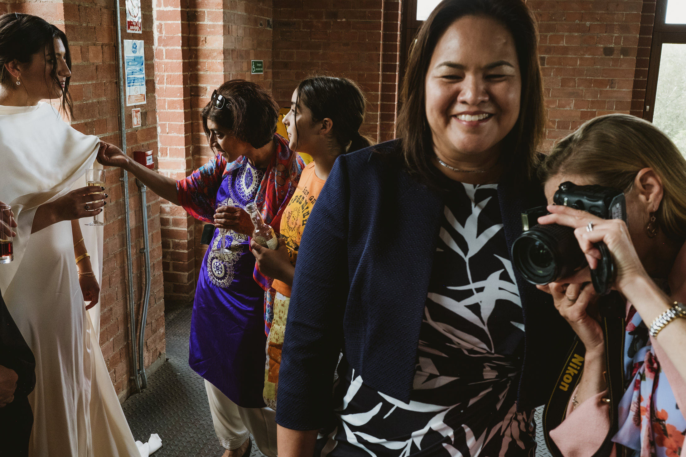 Group enjoying wedding, photographer captures moment.
