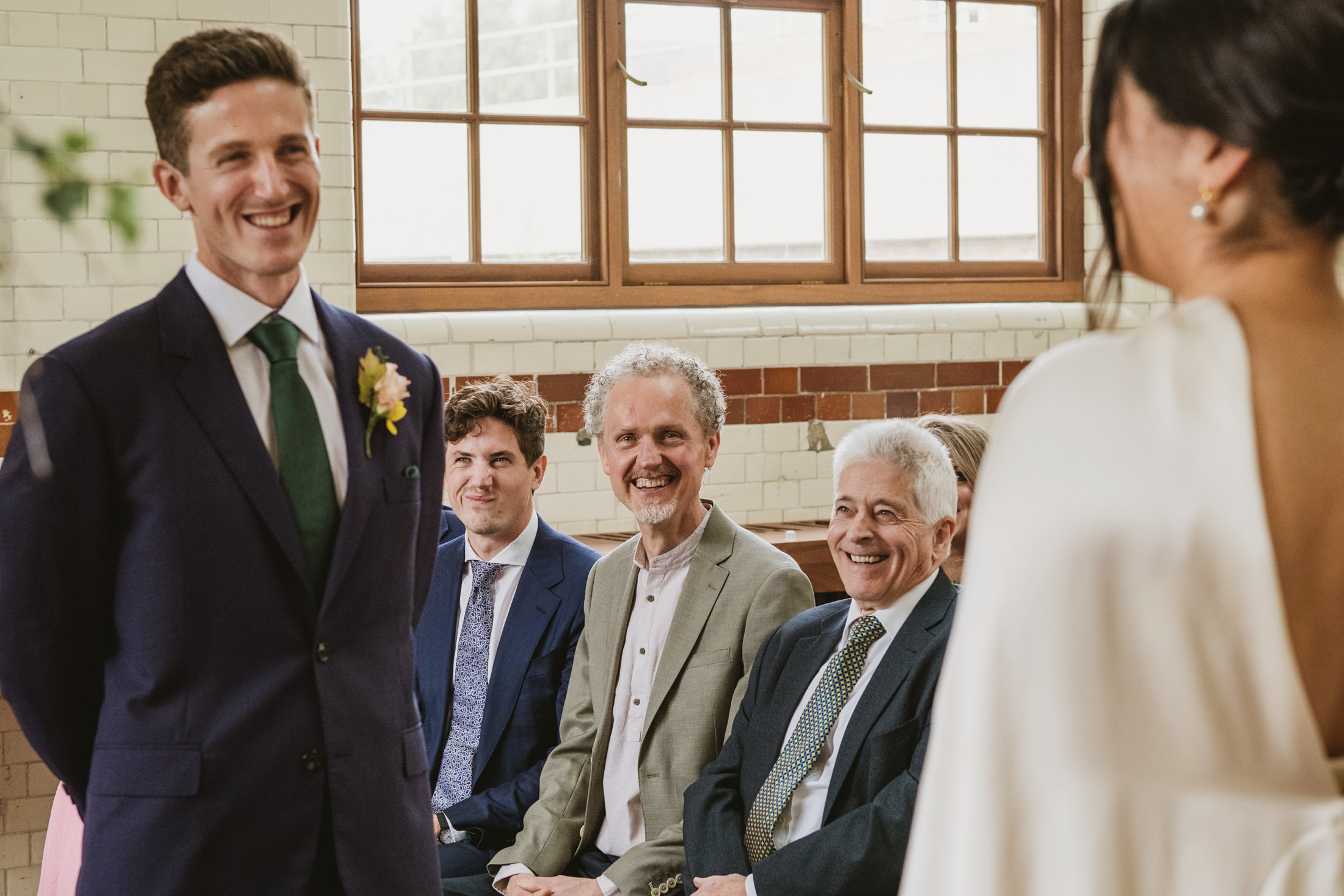 Smiling groom and guests at wedding ceremony.
