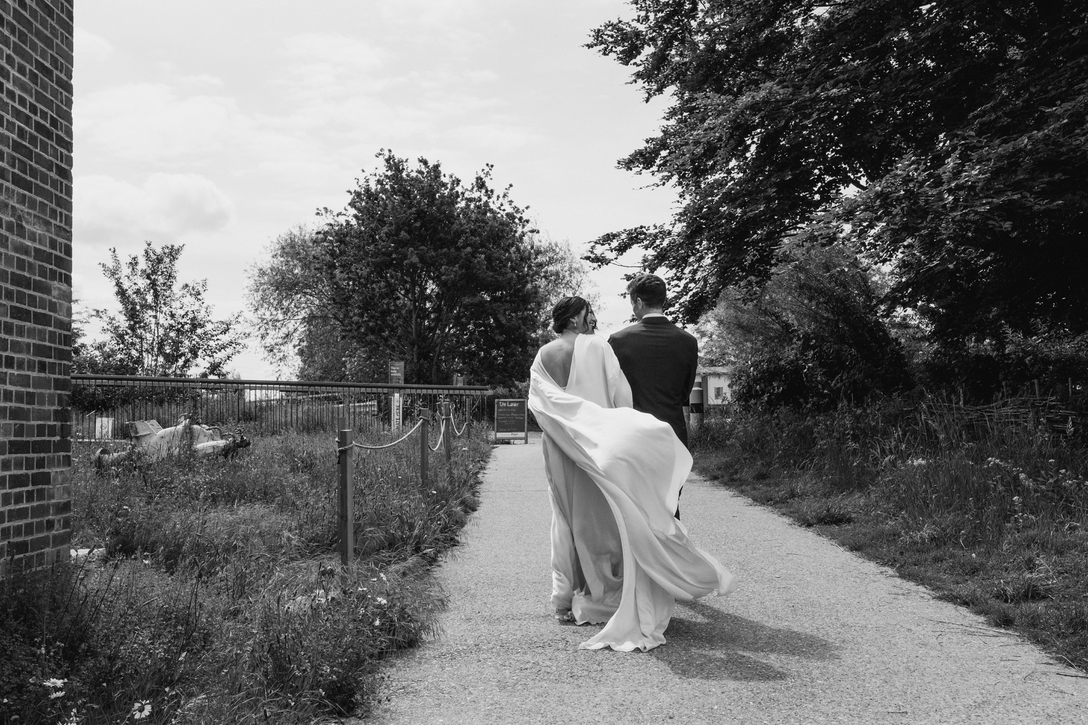 Wedding couple walking in windy park, black and white.