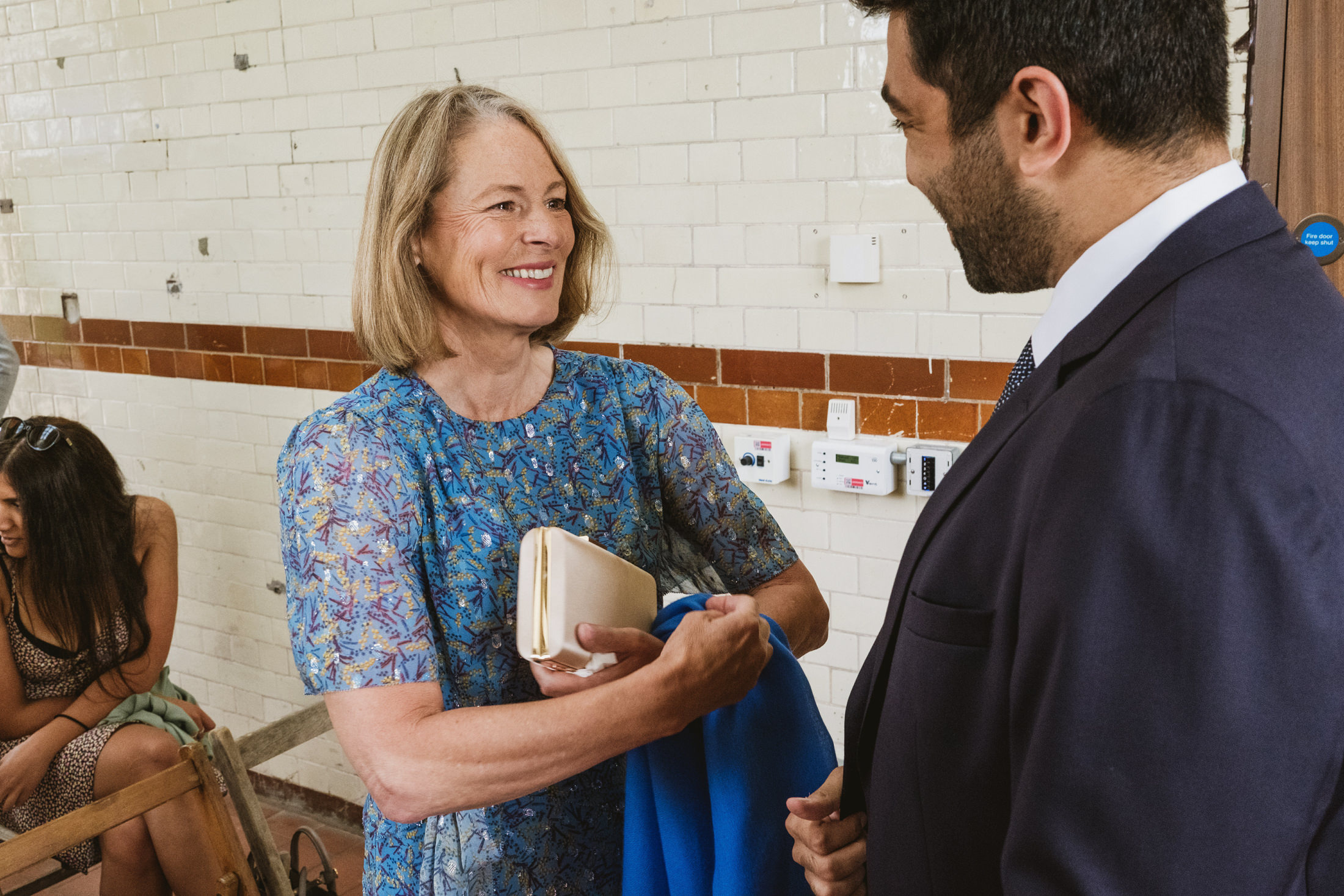 Two people smiling and talking indoors.