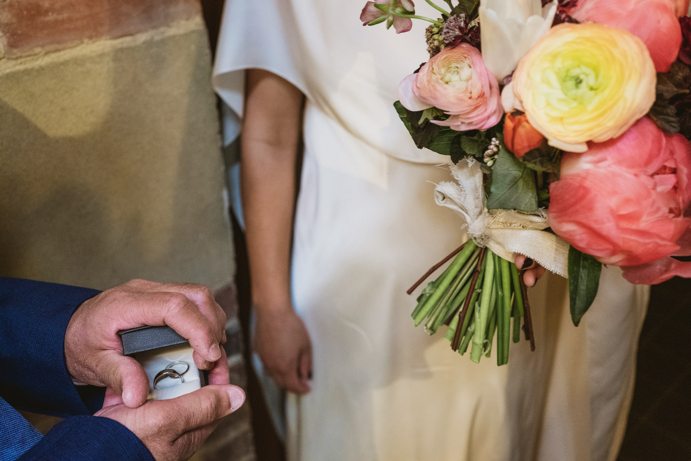 Man presenting wedding ring to bride with bouquet.