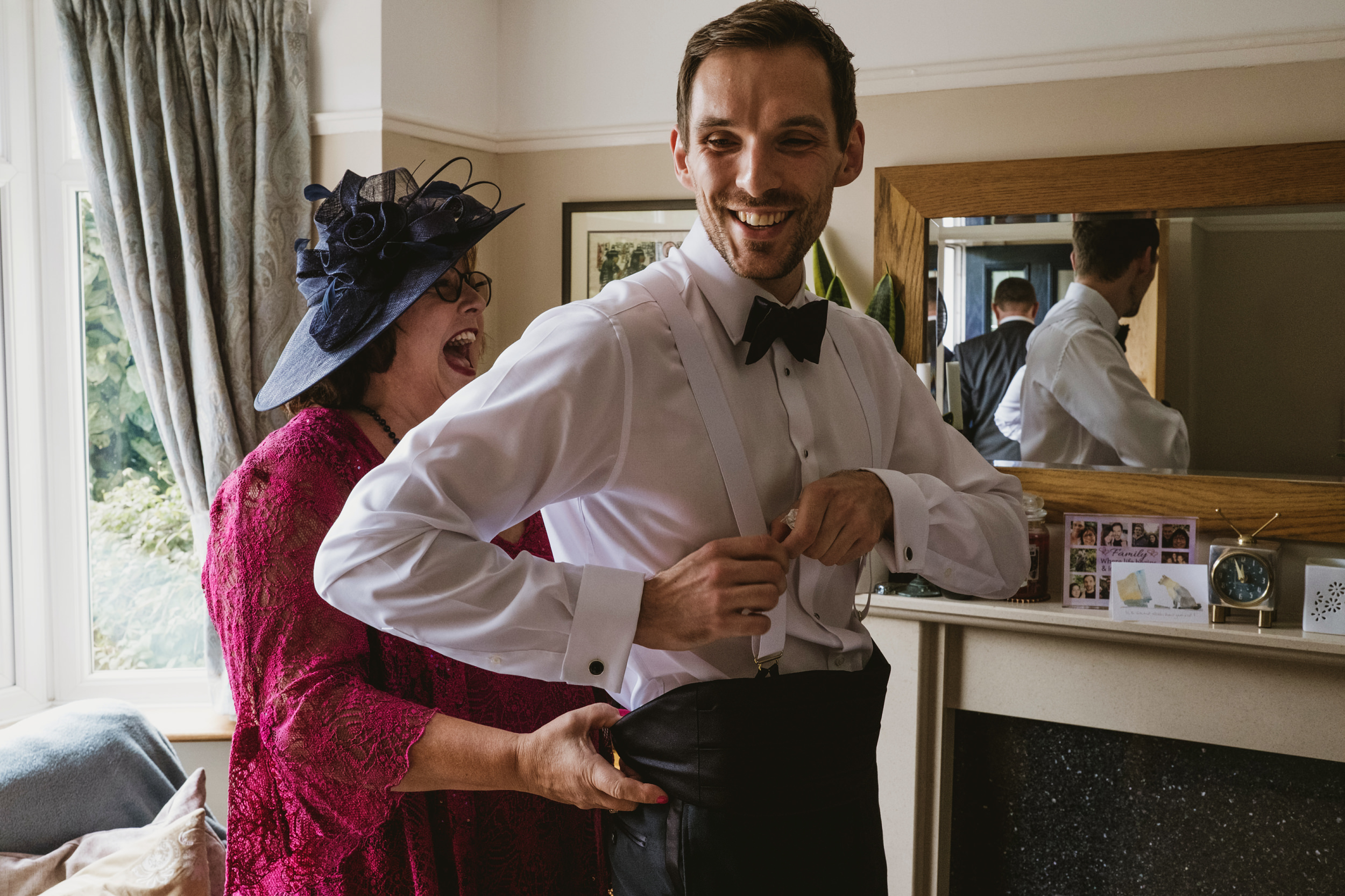 Mother helps groom with suit on wedding day.