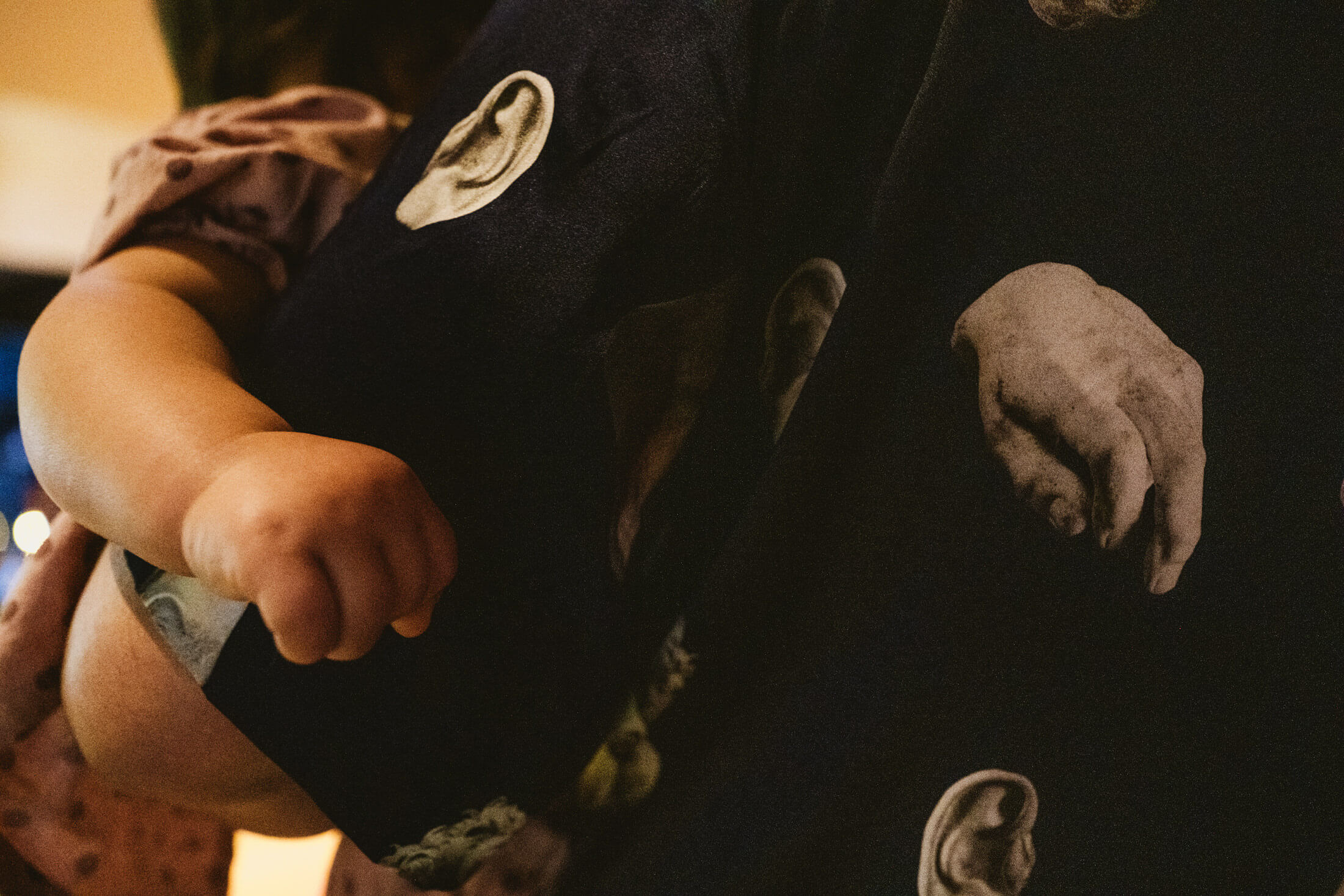 Child’s arm wrapped around adult’s waist in warm light, candid wedding photography moment.