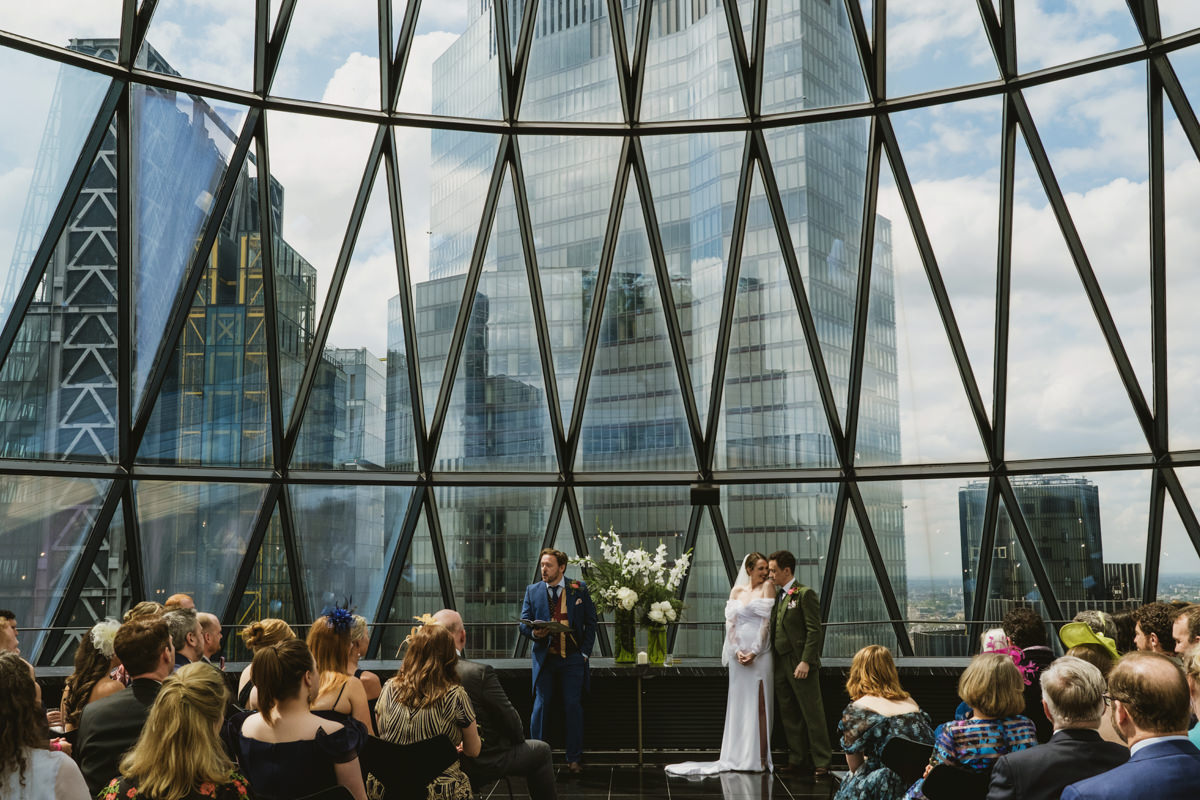 Wedding ceremony inside modern glass building in London.