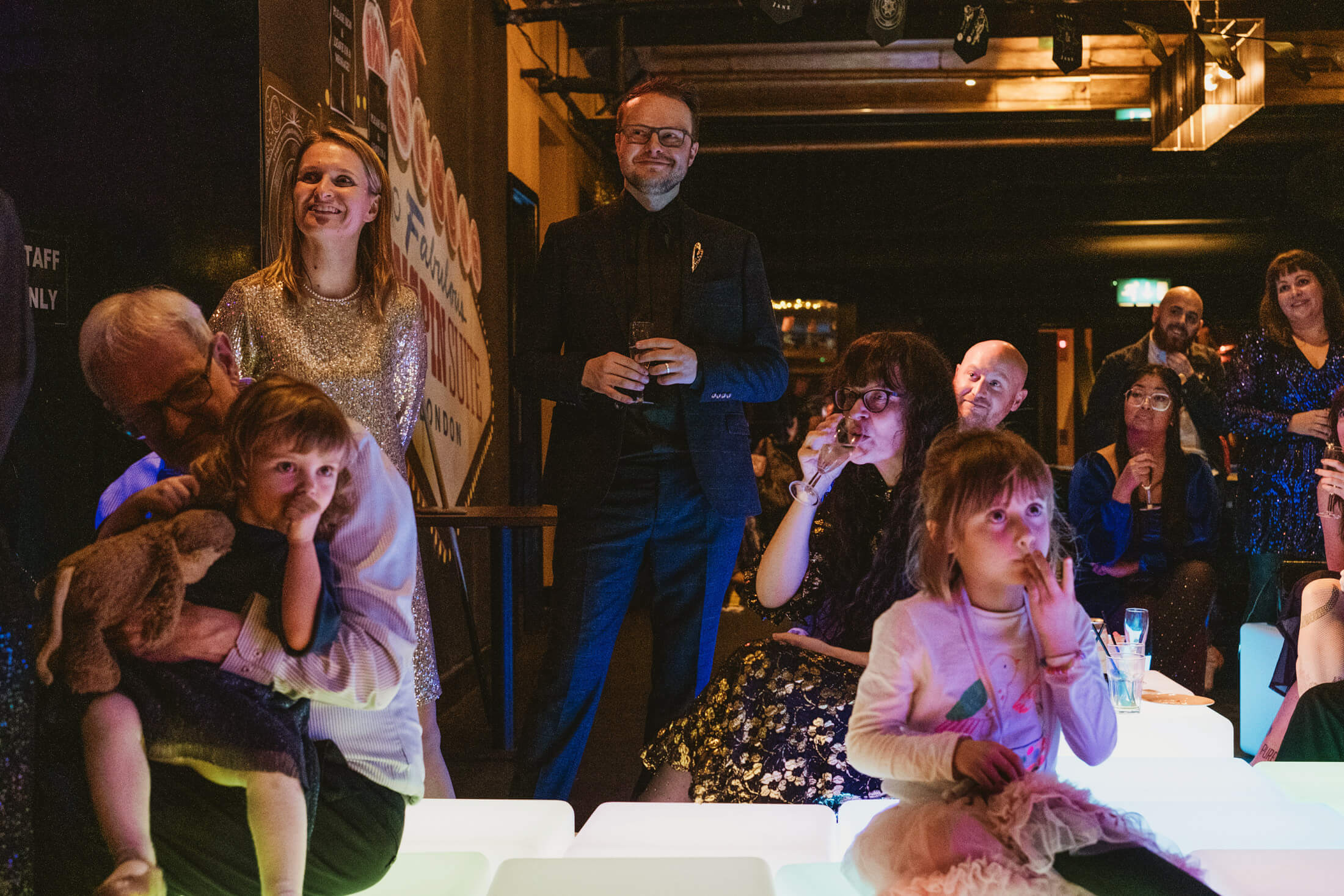 Guests and children gathered under warm lights at a documentary wedding reception