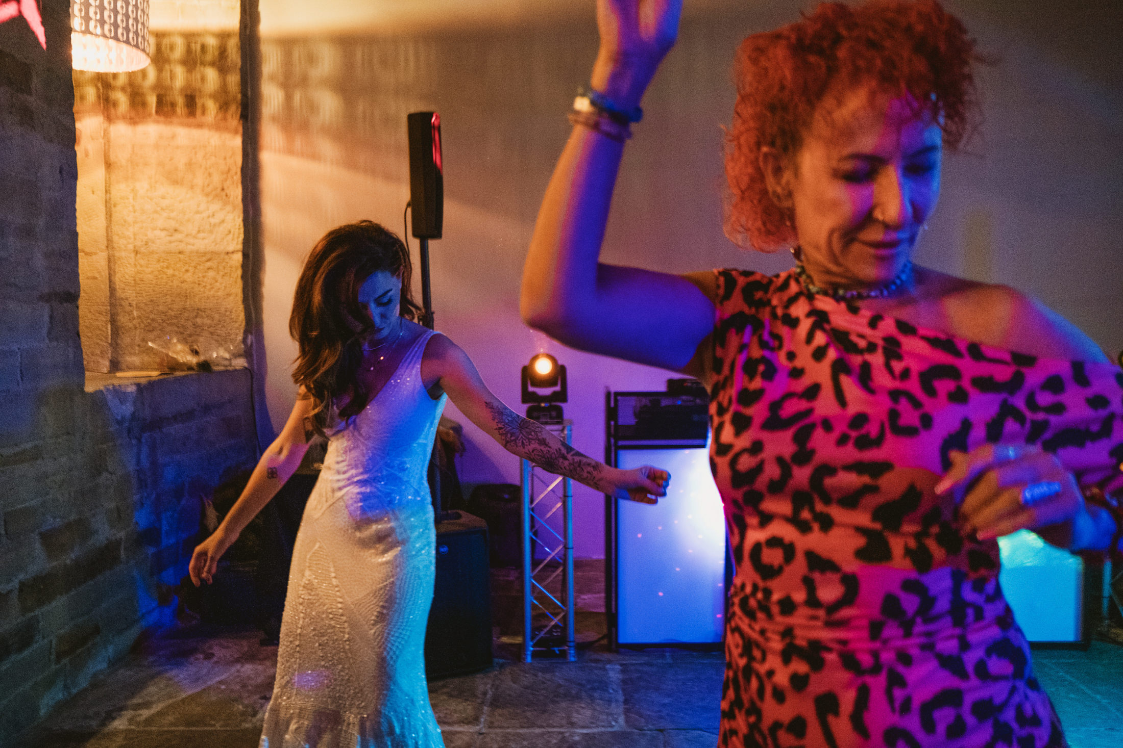 Bride and guest dancing beneath colourful lights at wedding reception, documentary wedding photography.
