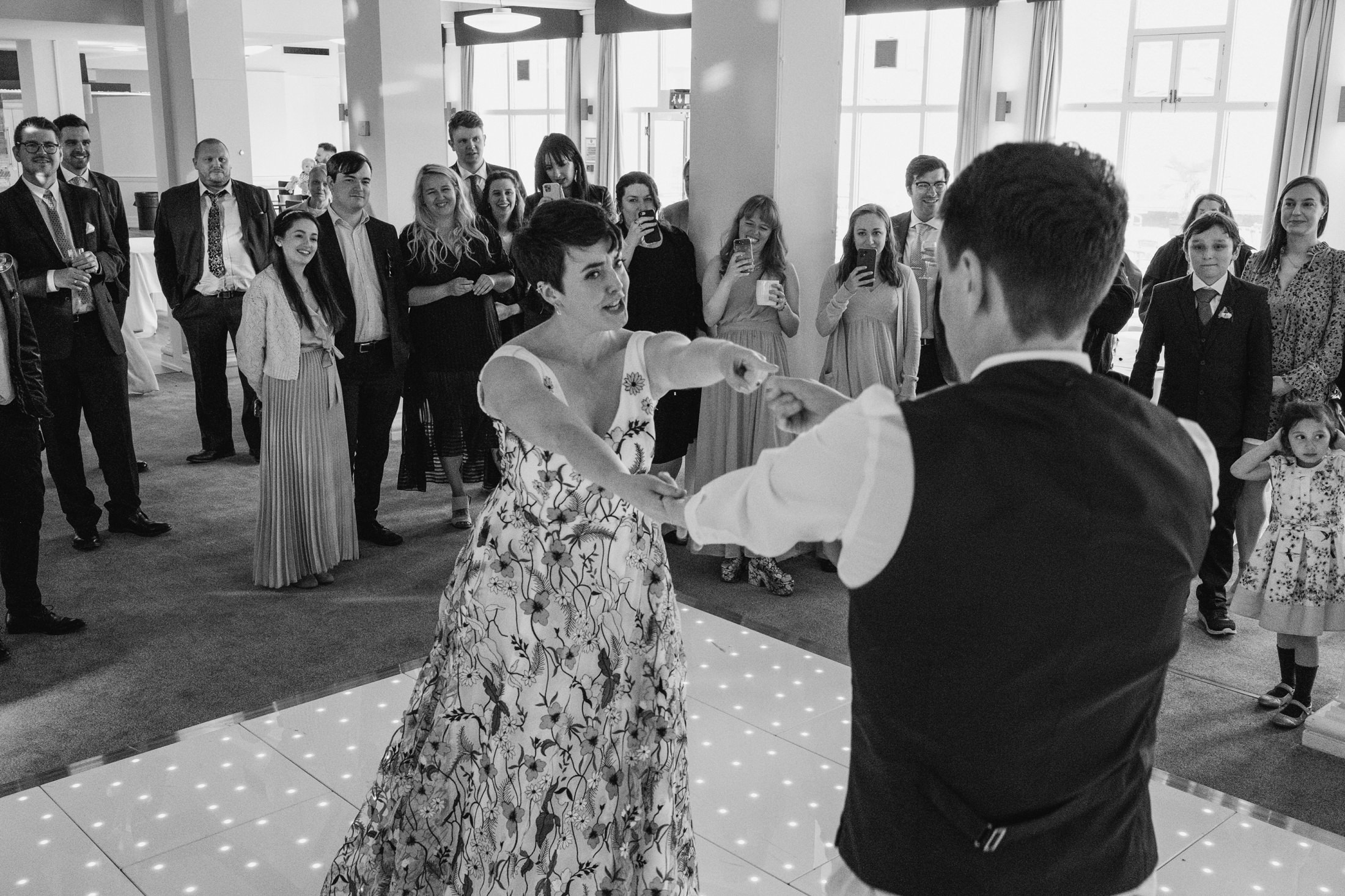 Couple dancing at wedding reception, guests watching.