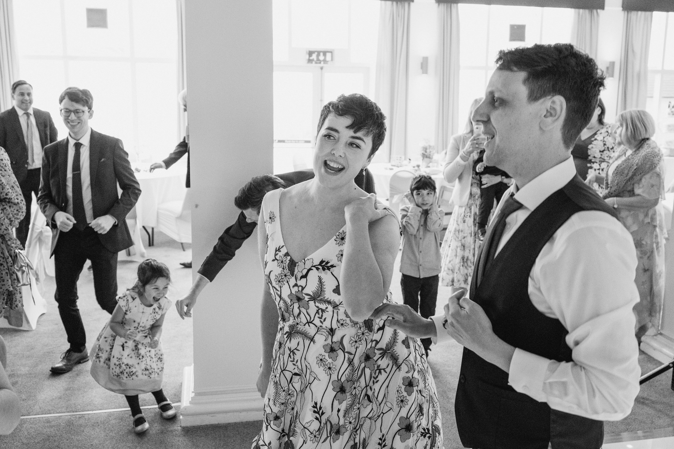 Wedding reception guests dancing and laughing.