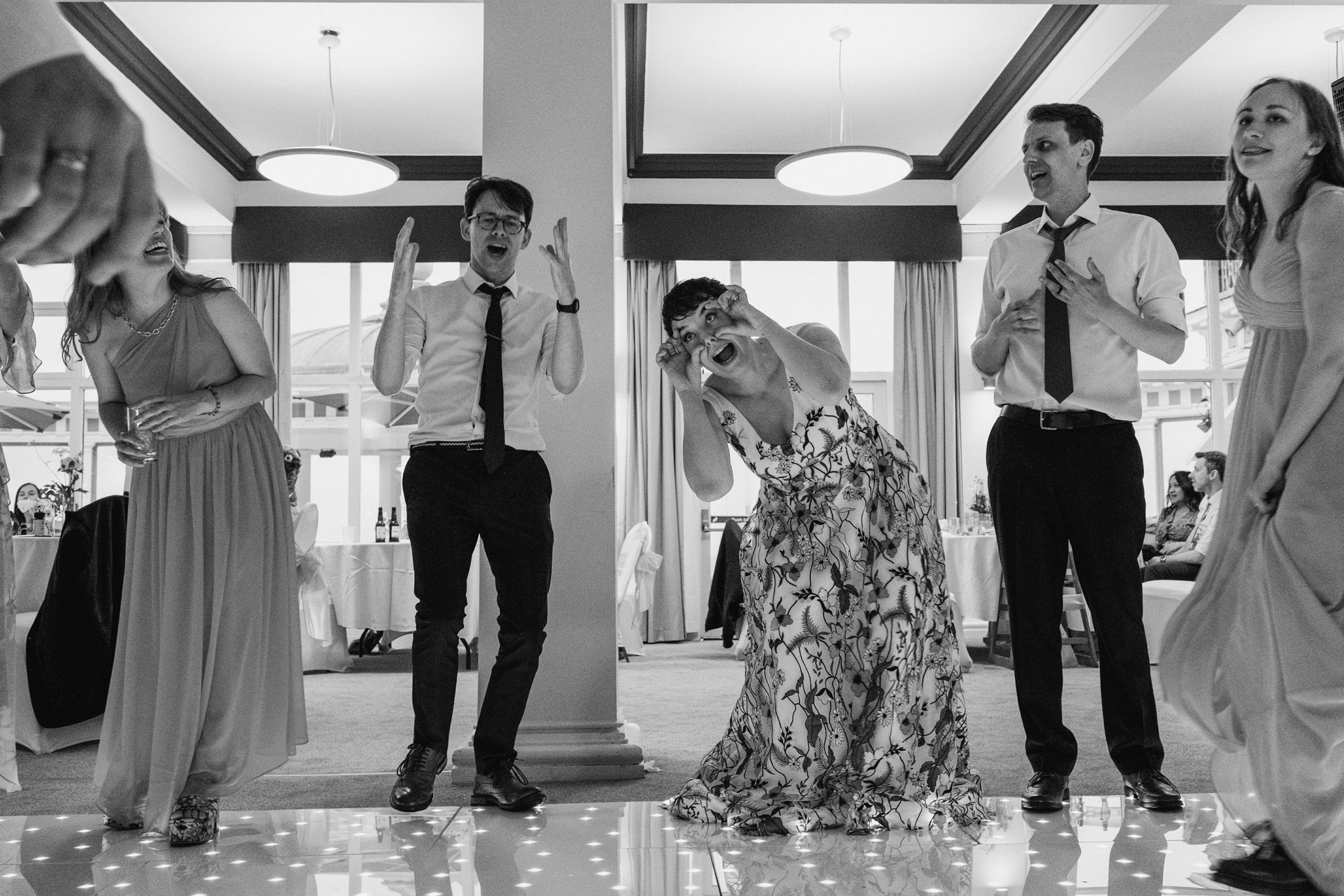 People dancing and laughing at a wedding reception.