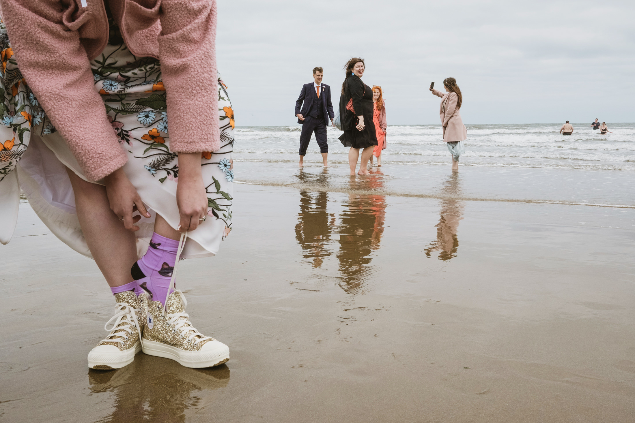 People enjoying a beach in spring clothing.