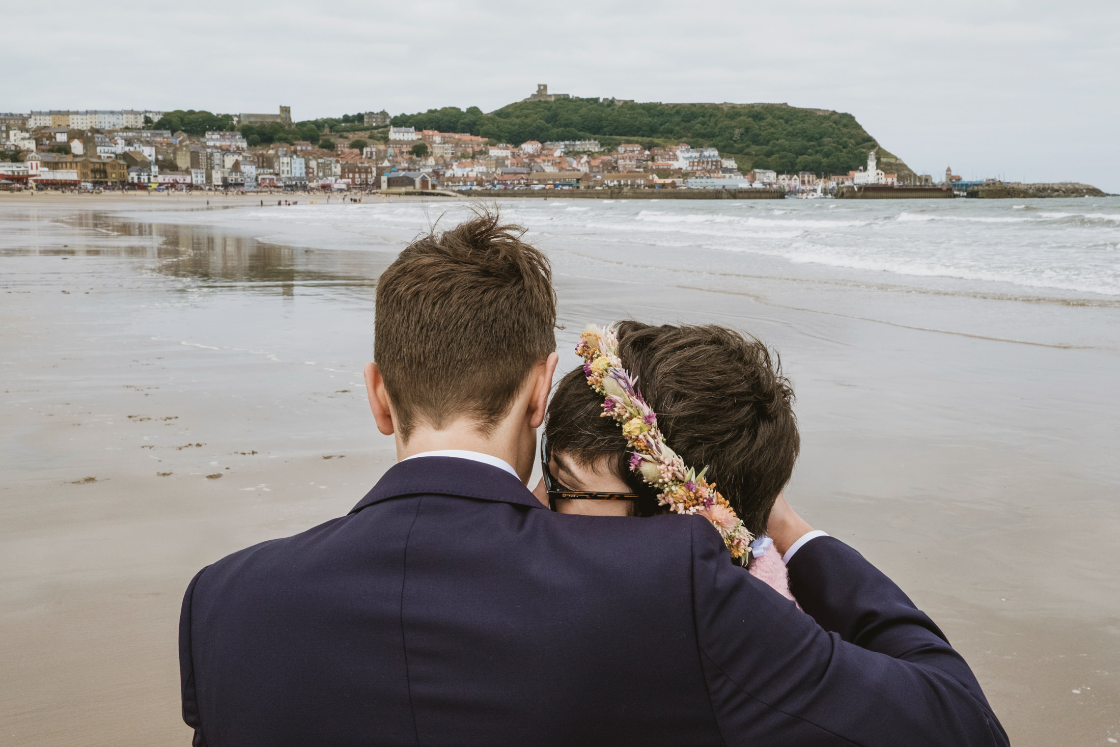 Couple on the beach with coastal town view.