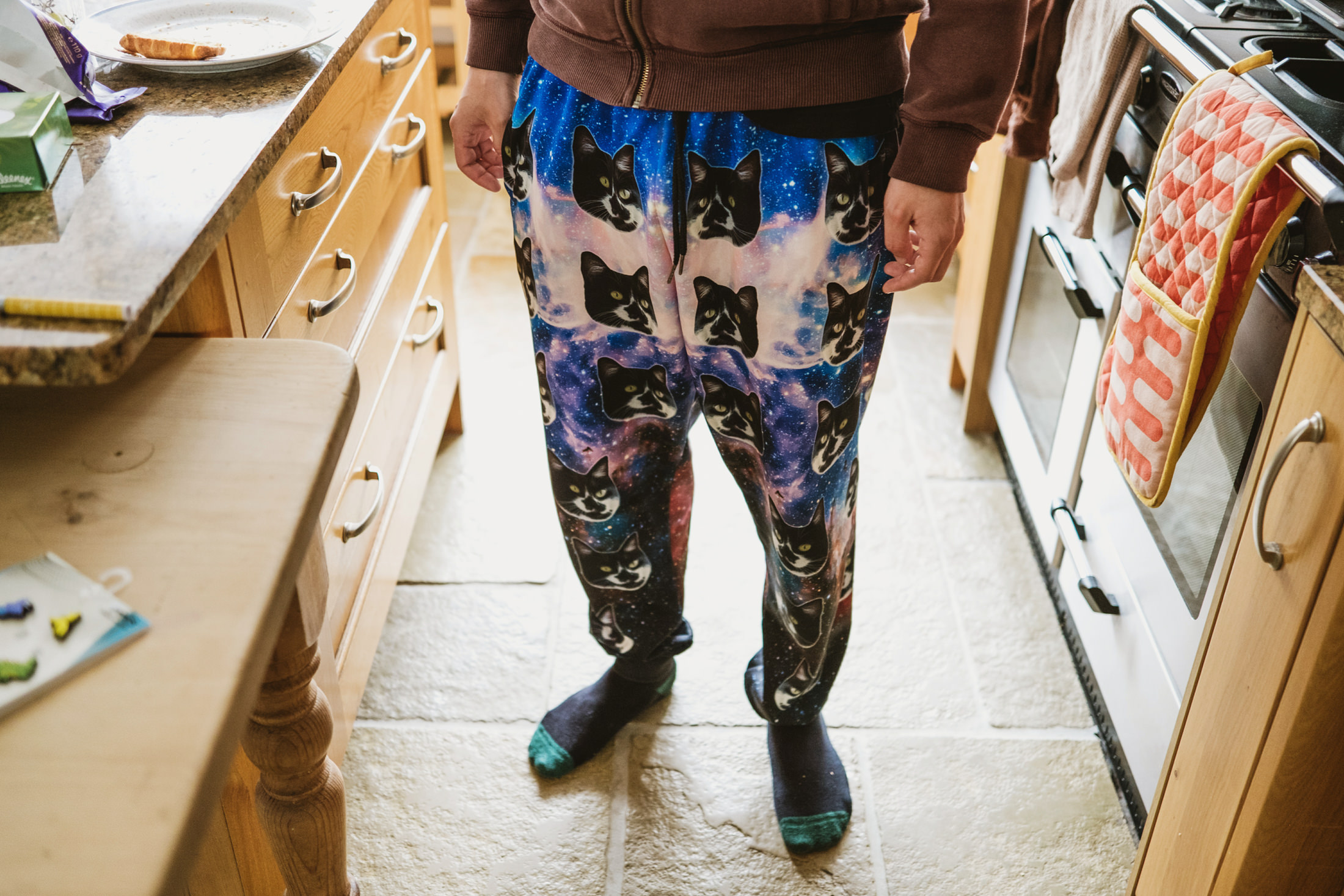 Person wearing cat print trousers in kitchen.