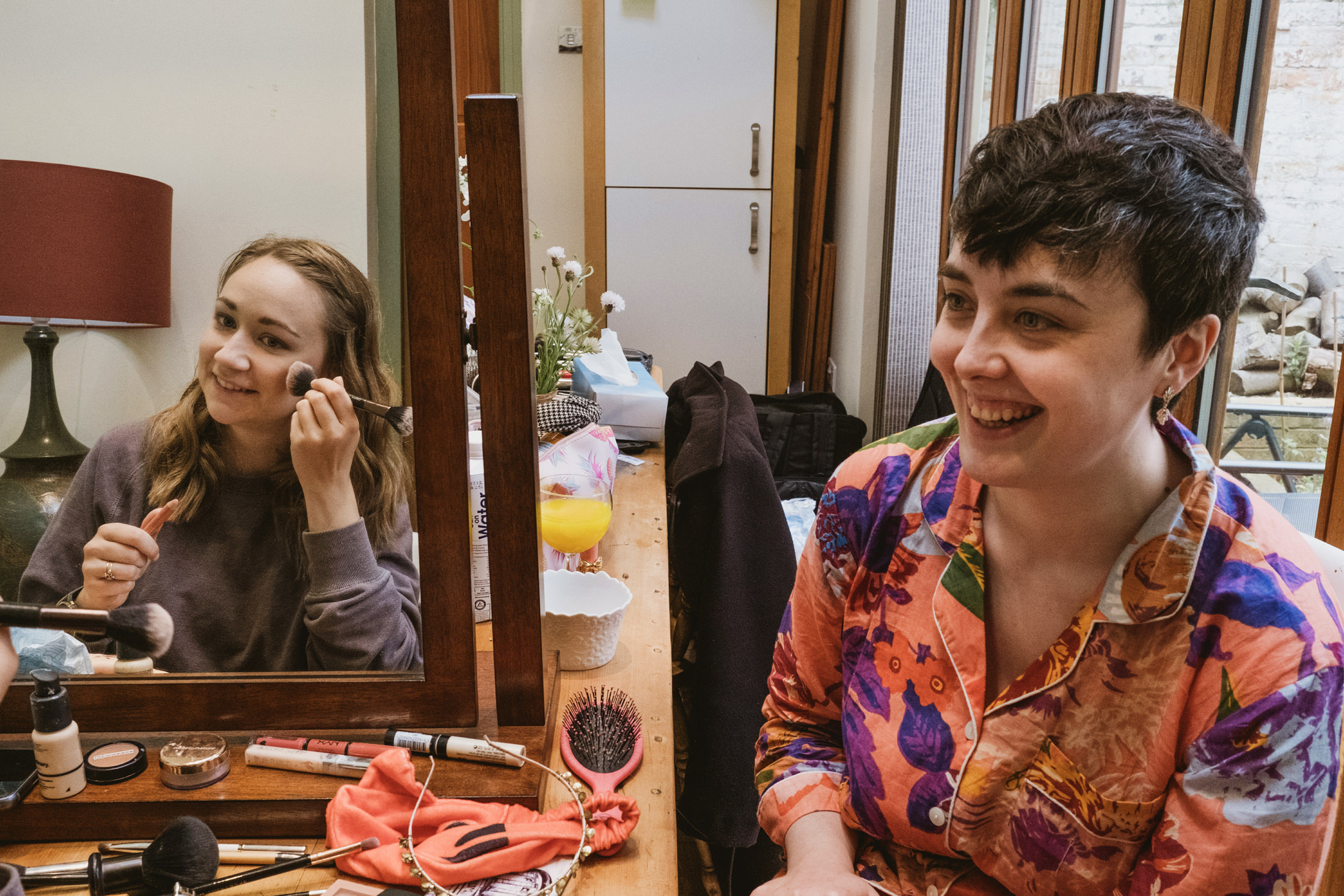 Two friends getting ready, applying makeup together.