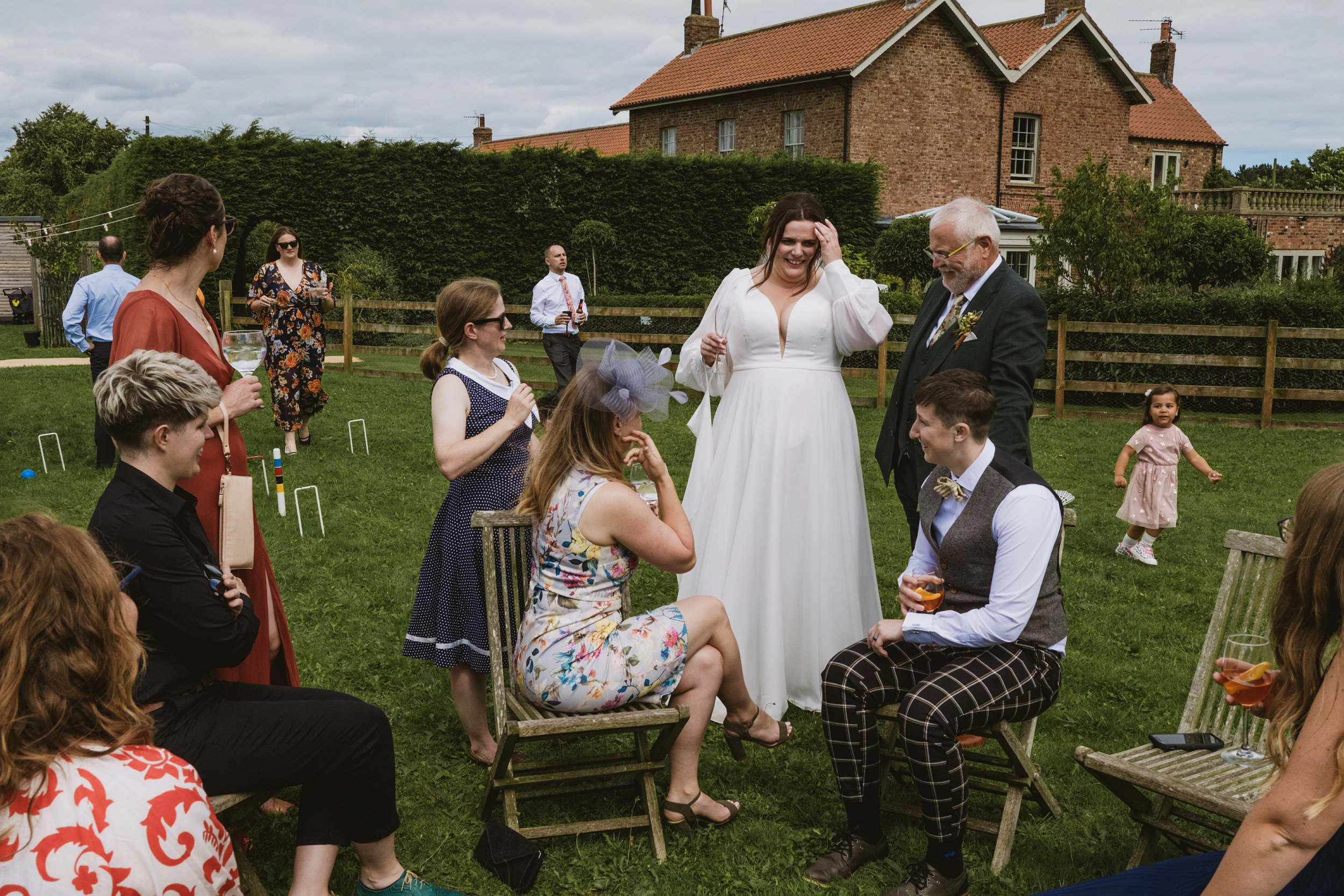 Outdoor wedding celebration with guests and bride laughing.
