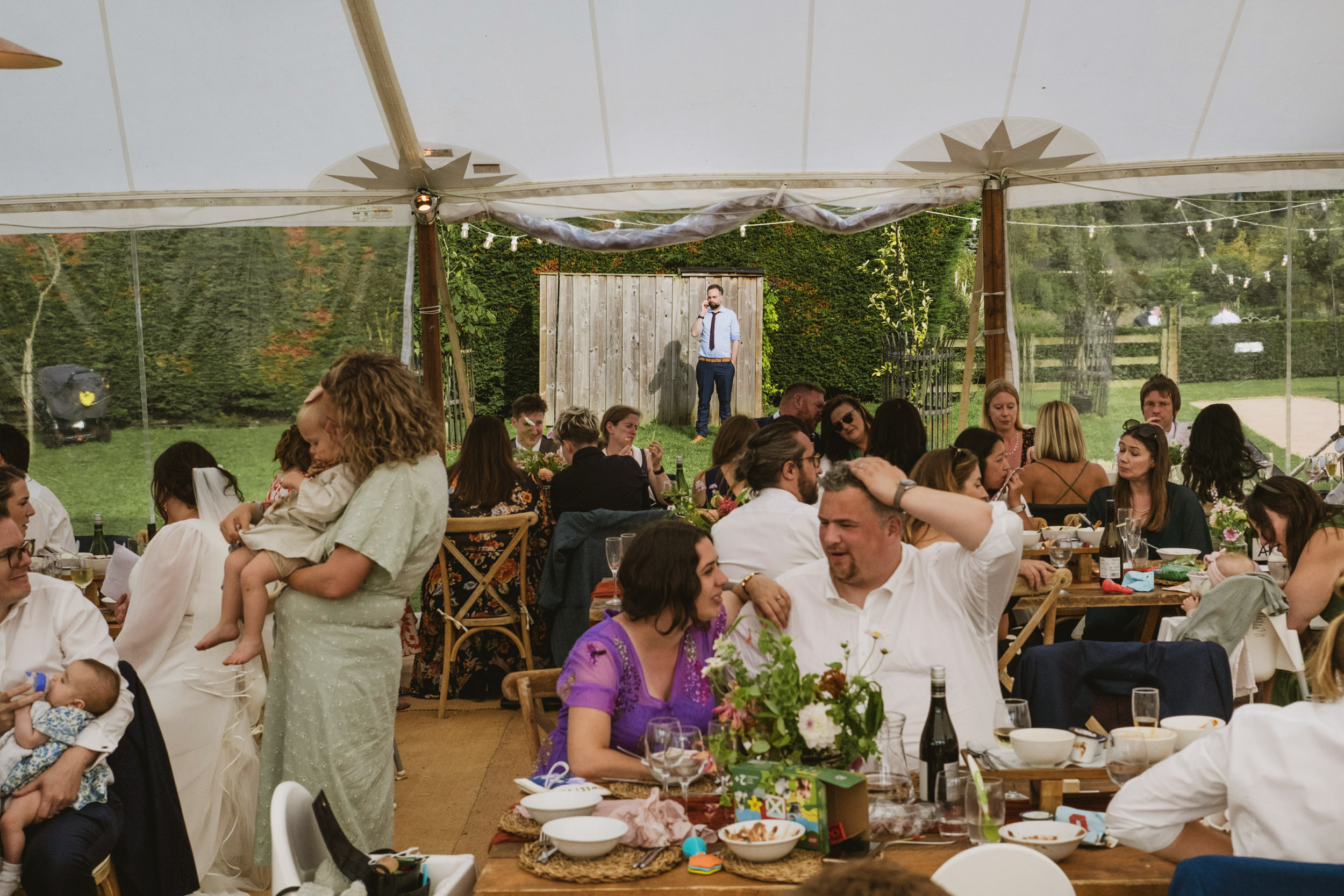 Guests enjoying outdoor wedding reception under tent.